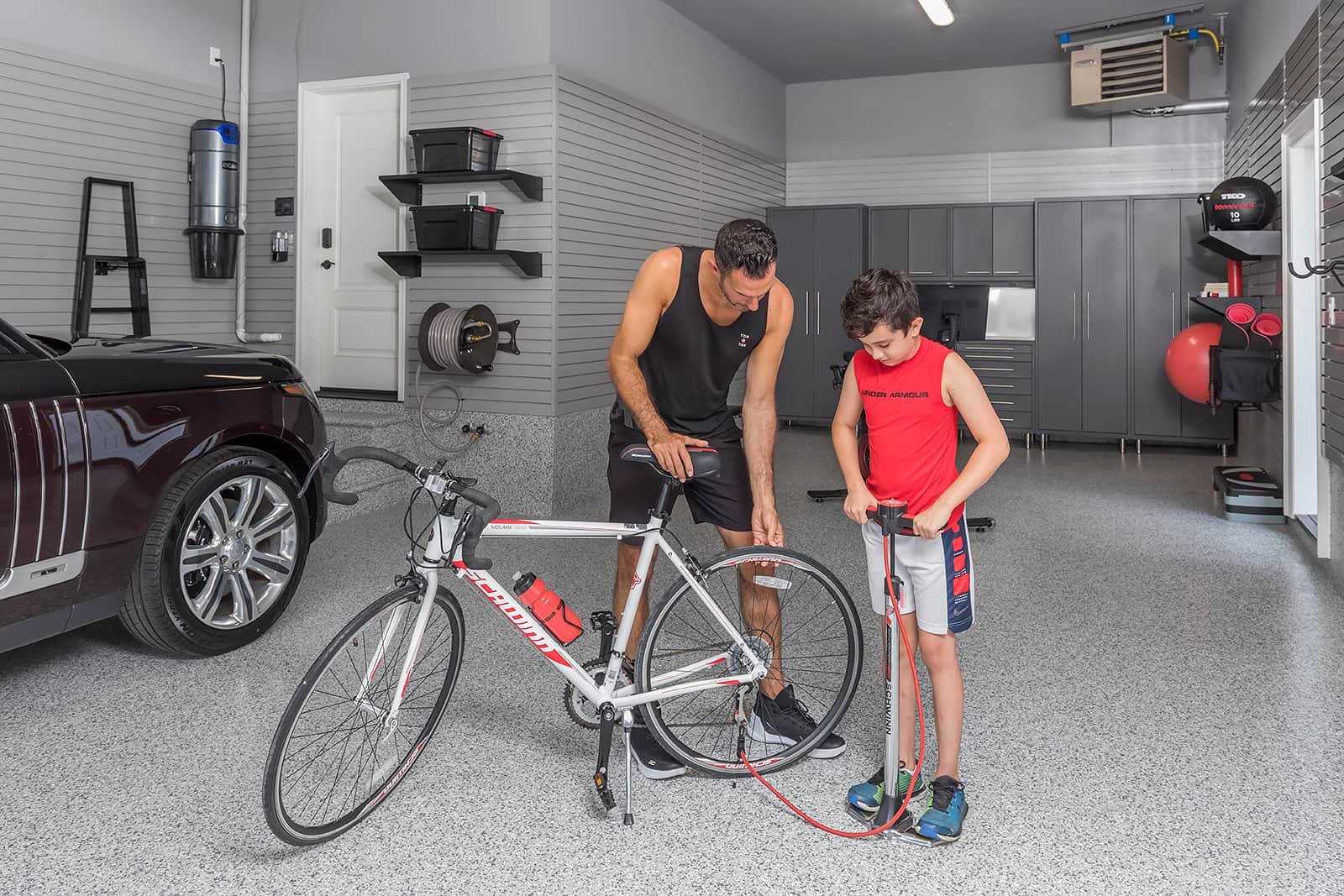 Father pumping his child's bike - The Fitness Room Garage - Garage Living