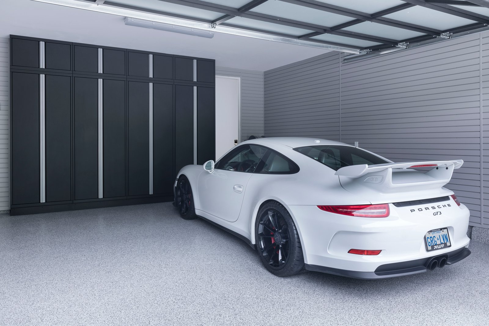 Minimalistic Garage with storage cabinetry and Porsche GT3 - Garage Living